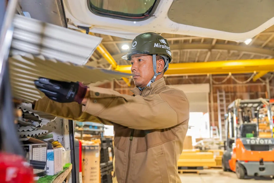 車両から波板材を取り出す職人の姿