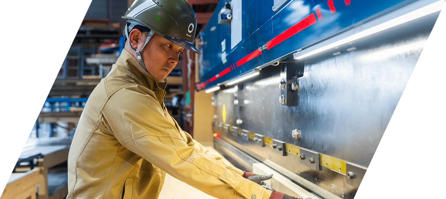 作業場で板金機械を扱うヘルメット着用の職人