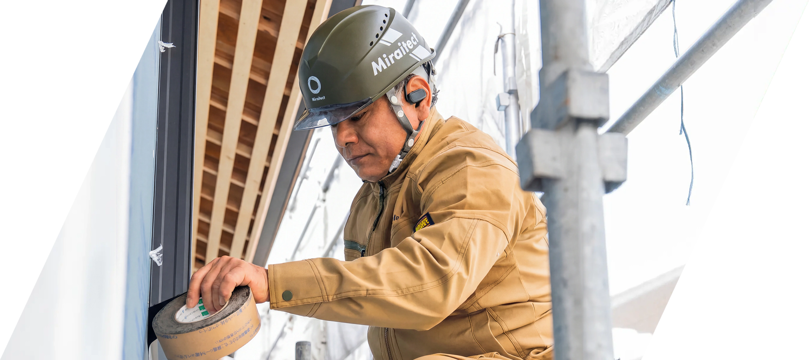 外壁面にテープを貼るヘルメット着用の職人